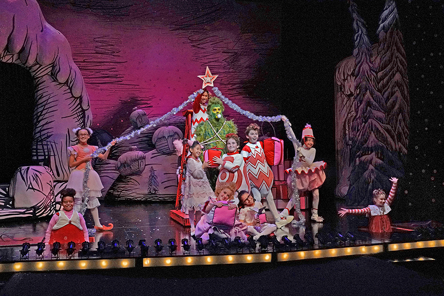 (center) Edward Watts appears as The Grinch with the cast of Dr. Seuss's How the Grinch Stole Christmas!, book and lyrics by Timothy Mason, music by Mel Marvin, original production conceived and directed by Jack O'Brien, original choreography by John DeLuca, and directed by James Vásquez, running November 3 – December 29, 2018 at The Old Globe. Photo by Ken Howard.